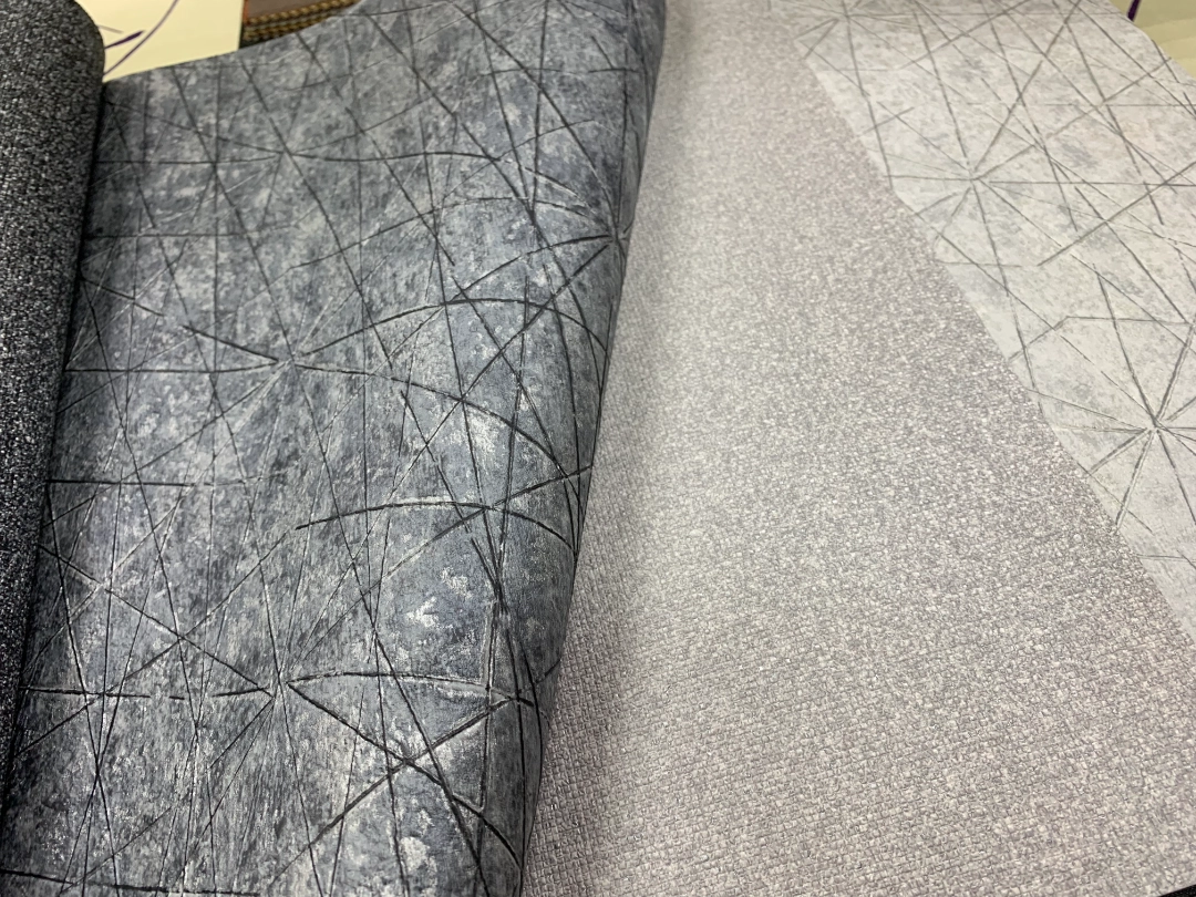 Muestras físicas de papel tapiz con texturas y colores neutros